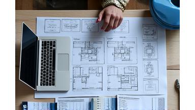 Detaljerte plantegninger og budsjettutkast vist på et bord med designverktøy